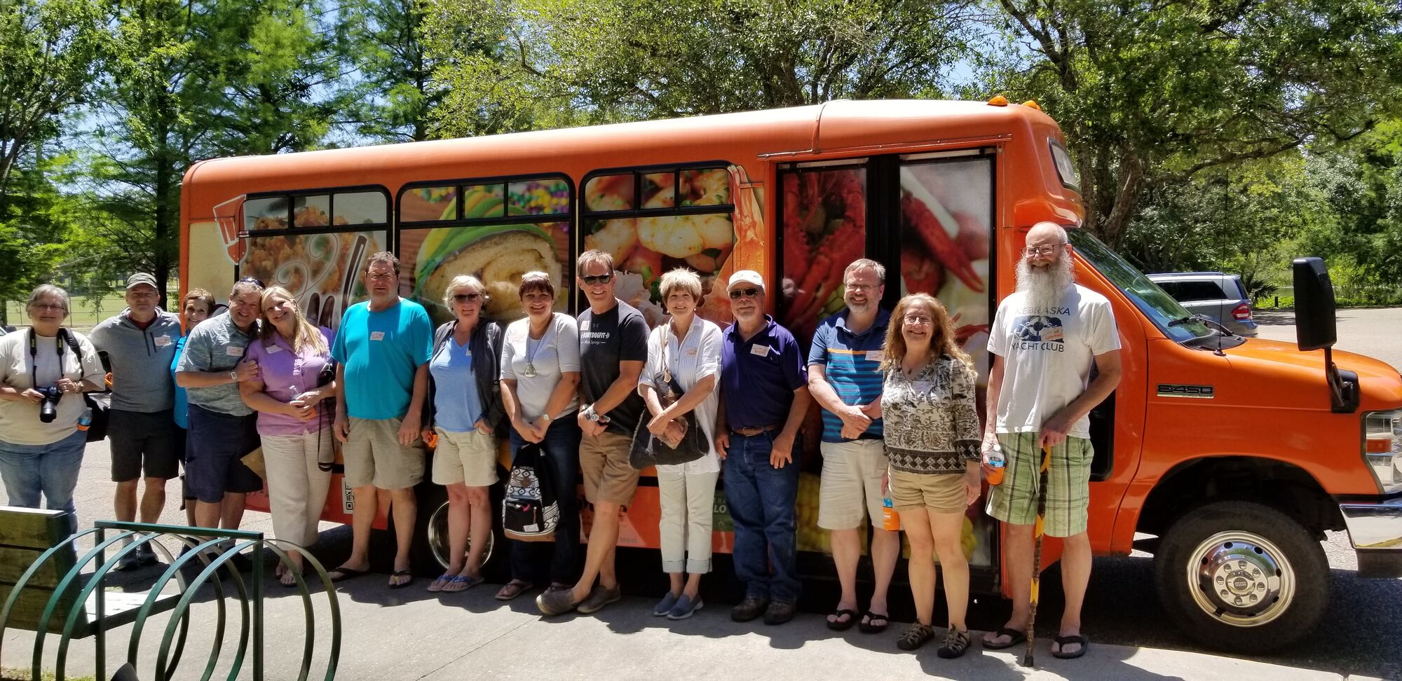 Guests gathered beside the orange Cajun Food Tours bus in Lafayette